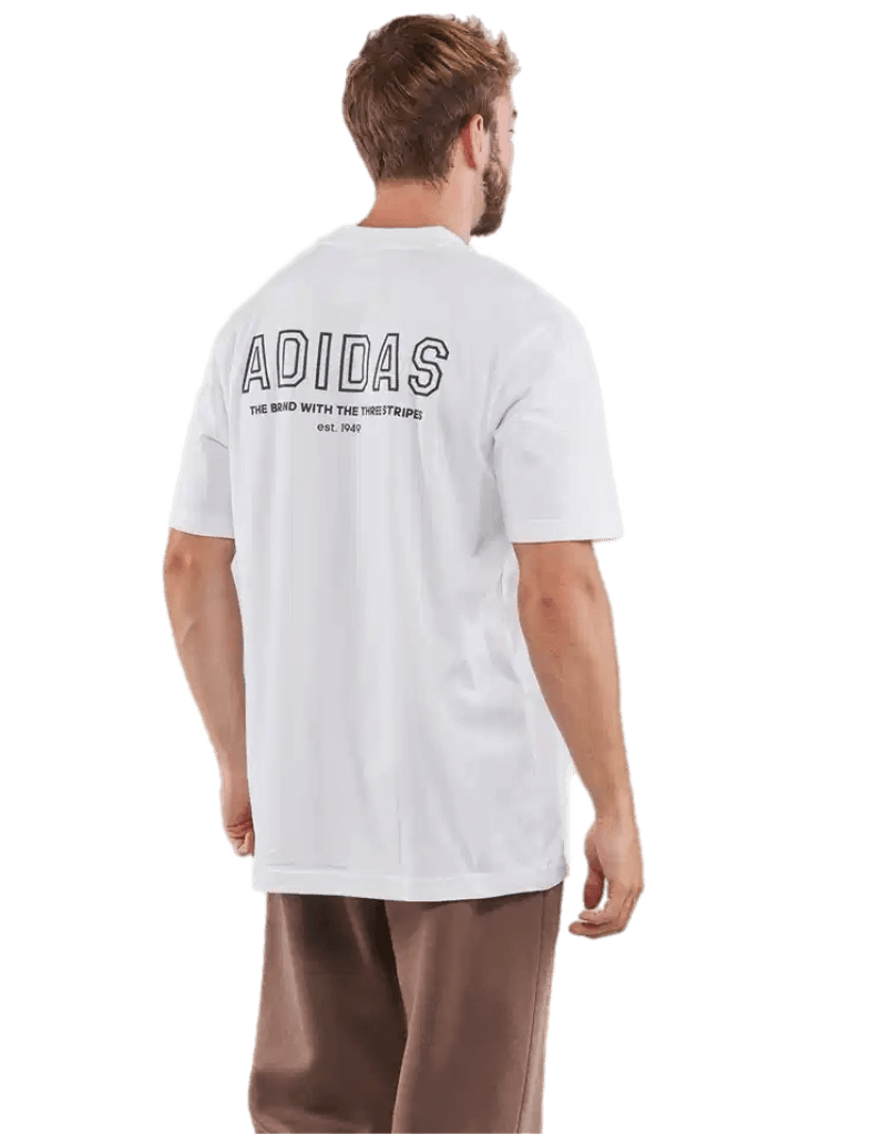 Back view of a man wearing a white Adidas Trefoil logo t-shirt paired with beige pants, casual streetwear style.